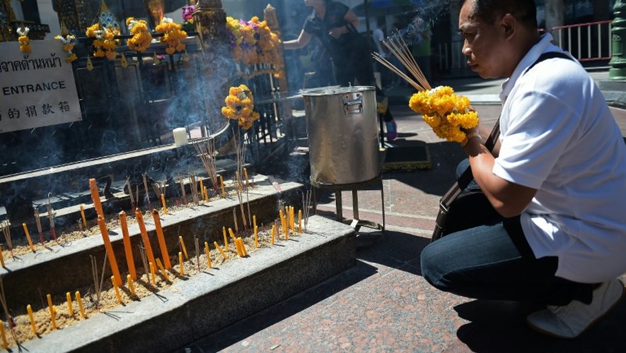 Un homme allume des bâtons d'encens et offre des prières au sanctuaire d'Erawan de Bangkok, lors de sa réouverture, le 19 août 2015, au surlendemain d'un attentat qui a fait 20 morts