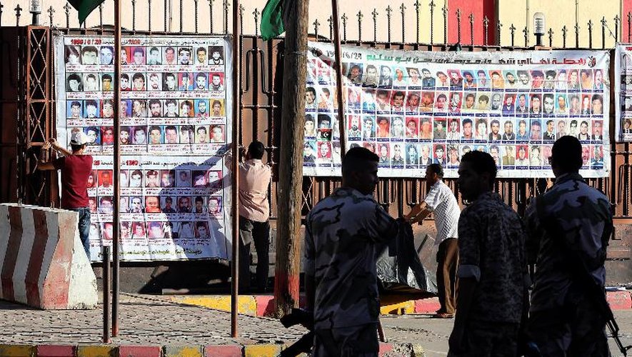 Des policiers passent devant des photos affichées par des proches de personnes tuées durant la répression en Libye, le 24 octobre 2013 à Tripoli