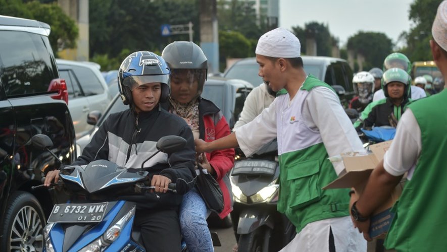 Des conducteurs reçoivent de la nourriture pour la rupture du ramadan, le 28 juin 2016 dans les rues de Jakarta grâce à une mosquée mobile qui sillonne la capitale