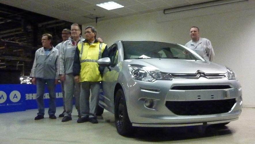 Des employés de PSA posent avec la dernière voiture produite dans l'usine d'Aulnay-sous-Bois, le 25 octobre 2013