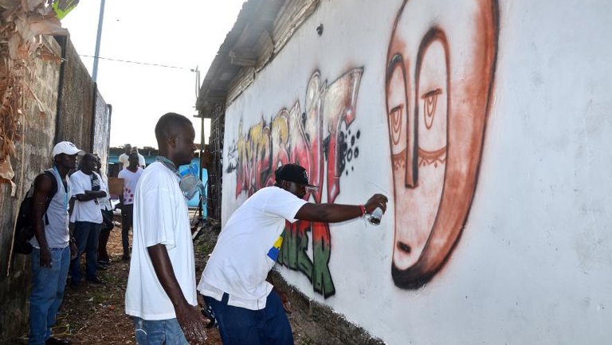 L'artiste gabonais Régis Divassa et d'autres artistes peignent un graffiti disant "Interdi d'uriner" sur un mur d'un quartier populaire de Libreville, le 10 octobre 2013