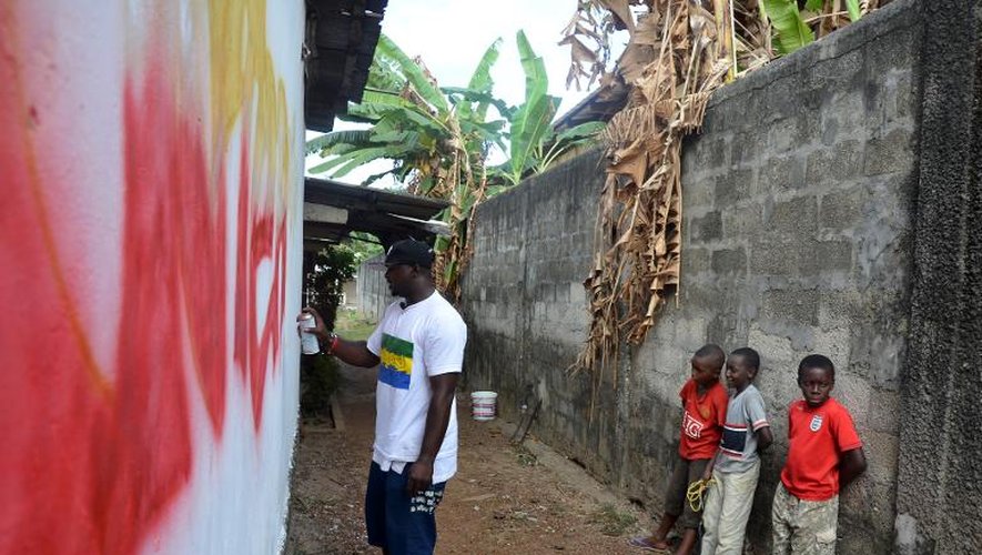 Des enfants regardent l'artise Régis Divassa peindre un graffiti sur un mur, le 10 octobre 2013 à Libreville