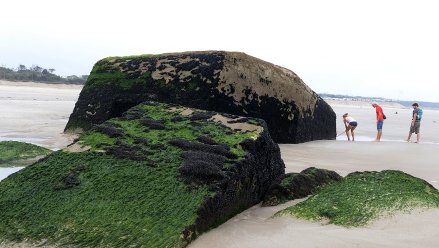 Des vacanciers observent les restes d'un bunker allemand du Mur de l'Atlantique, découvert à marée basse sur la plage de Soulac (Gironde), le 13 août 2015