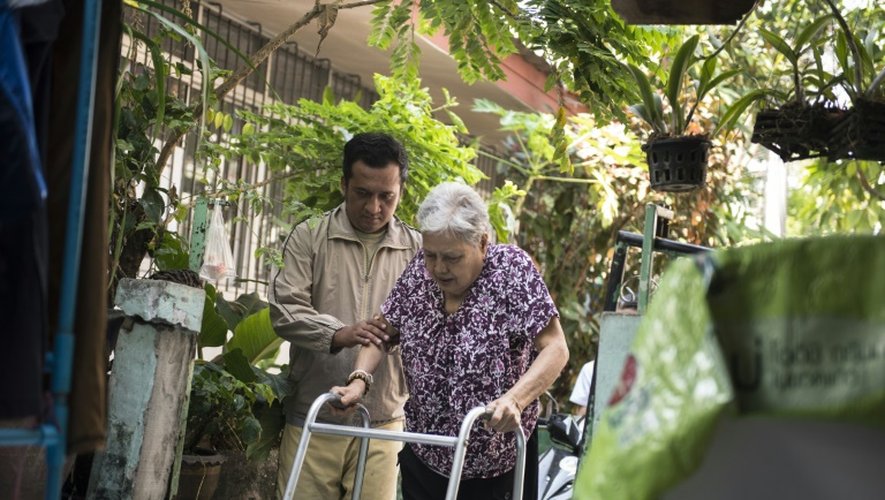 Nakhon Thianprasert (g) aide sa vieille tante de 77 ans  Boonrod Khamhomkul (d) à rentrer chez elle après une journée passée dans un centre de soins à Bangkok, le 3 mars 2016