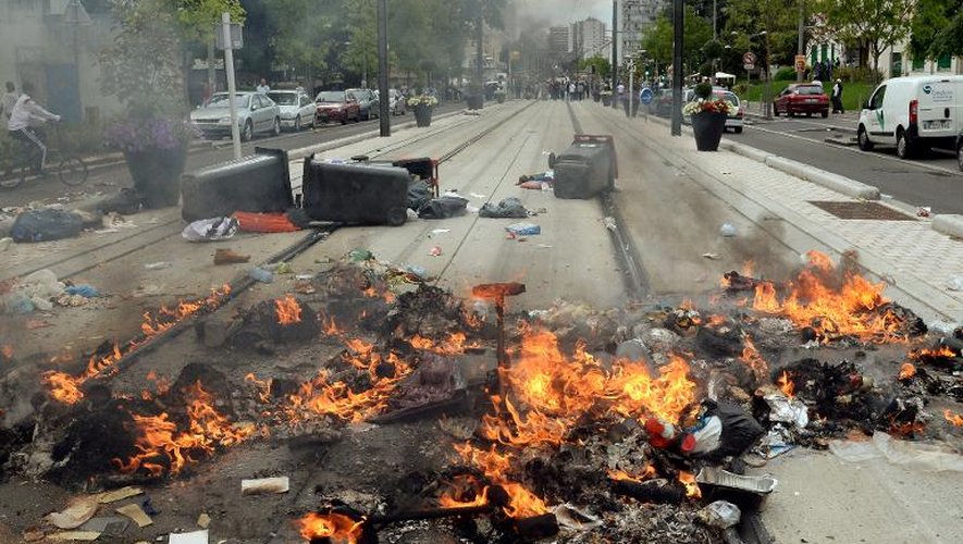 Des poubelles brulent le long des voies du tram le 20 juillet 2014 à la suite de heurts entre police et émeutiers à Sarcelles, dans la banlieue parisienne, en marge d'une manifestation pro-palestinienne qui a été interdite