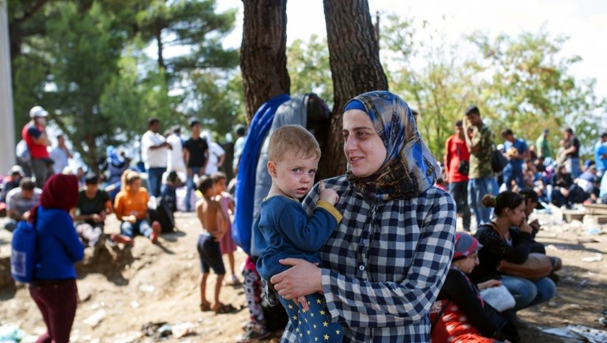 Une femme et son fils attendent comme les autres migrants à passer la frontière vers l'Europe du nord, le 20 août 2015 à Gevgelija, en Macédoine