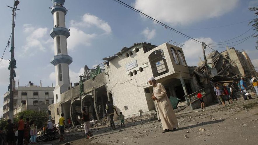 Des Palestiniens se rassemblent près d'une mosquée à Rafah (sud de la bande de Gaza), partiellement détruite par des raids israéliens, le 22 juillet 2014