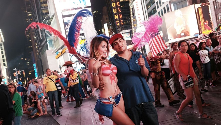 Une femme seins nus pose avec des touristes à Times Square à New York le 19 août 2015