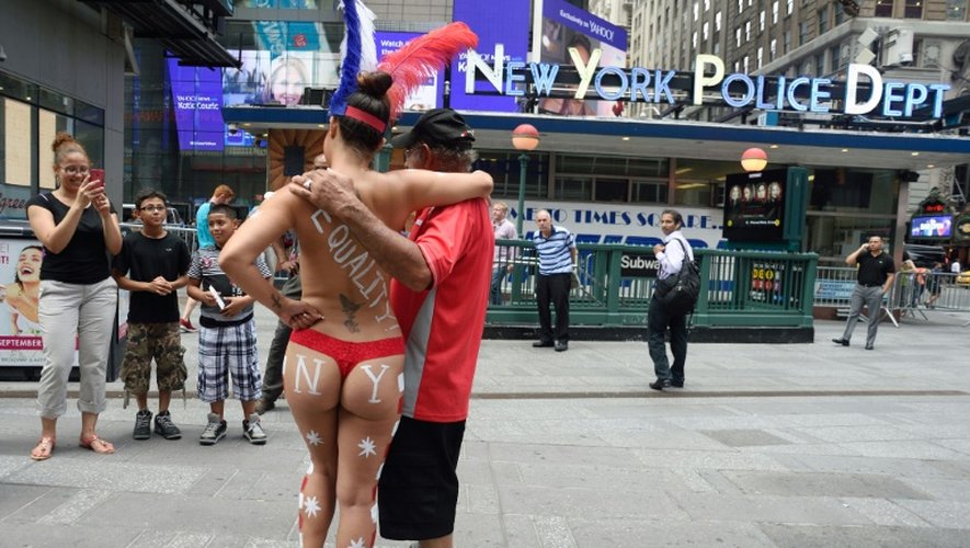 Une femme seins nus pose avec des touristes à Times Square à New Yok le 19 août 2015