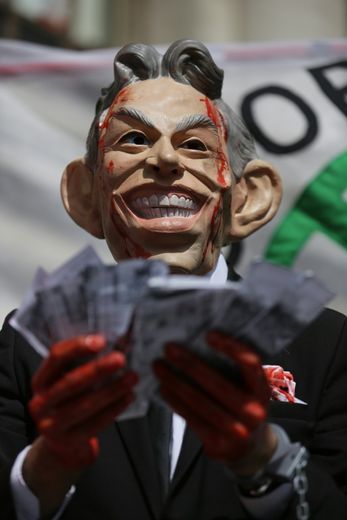 Un manifestant porte un masque de Tony Blair les mains ensanglantées pour protester contre son rôle dans la guerre en Irak, à Londres le 6 juillet 2016