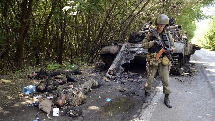 Un rebelle prorusse devant le corps d'un militaire ukrainien et d'un char détruit le 22juillet 2014 à Donetsk
