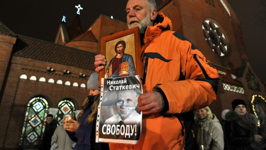 Un homme montre une icône et le portrait de Mikola Statkevitch lors d'une manifestation près de la cathédrale catholique de Minsk le 19 janvier 2011