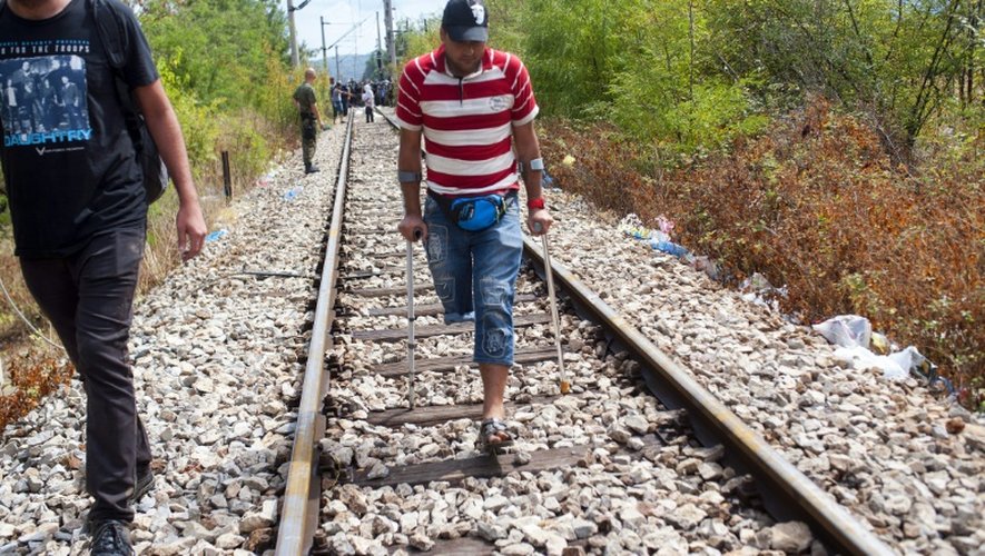 Des migrants marchent sur une voie ferrée vers la ville de Gevgelija après avoir forcé un cordon des forces spéciales de la police macédonienne à la frontière avec la Grèce le 22 août 2015
