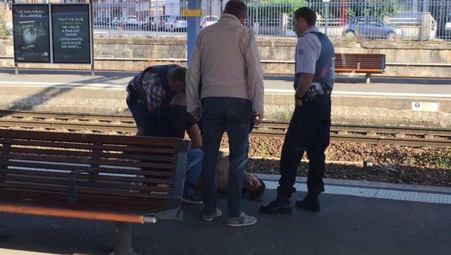 Photo prise par un passager avec un smartphone à travers la vitre d'un train Thalys montrant la police arrêtant un suspect sur le quai de la gare d'Arras le 21 août 2015
