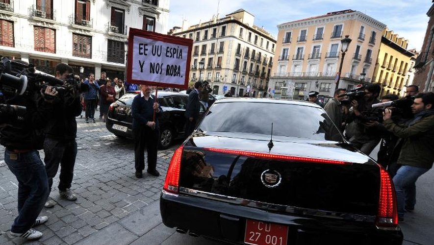 Un homme tient une pancarte "Les Etats-Unis nous espionnent et nous volent" devant la voiture de l'ambassadeur américain en Espagne James Costos, le 28 octobre 2013 à Madrid