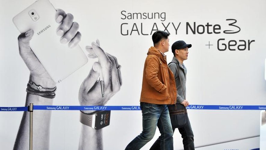 Deux hommes marchent devant un panneau publicitaire pour un smartphone Samsung à Séoul, le 25 octobre 2013