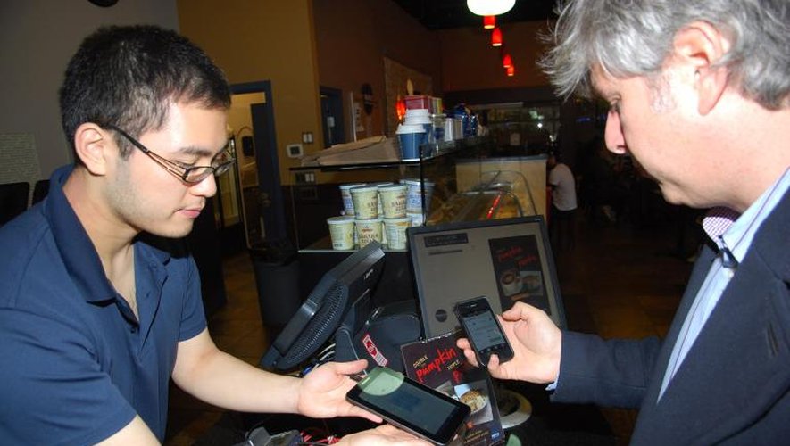 David Lowy (D) utilise son smartphone pour régler sa consommation en bitcoins, dans un café de Vancouver le 29 octobre 2013