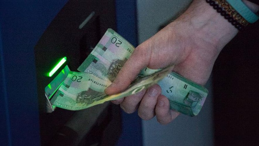 Un Canadien insère des billets dans une borne d'échange pour obtenir des "bitcoins", le 29 octobre 2013 à Vancouver