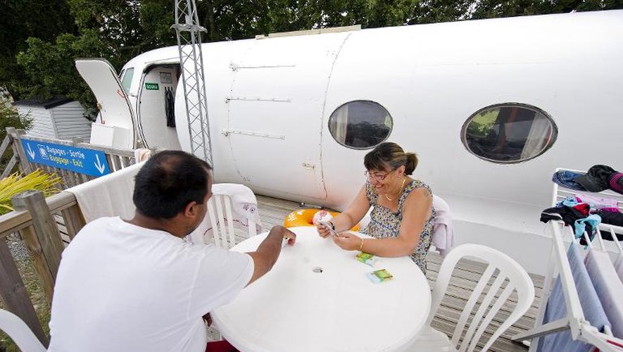 Des touristes jouent au carte près d'un modèle d'avion le 15 juillet 2014 à Saint-Michel-Chef-Chef