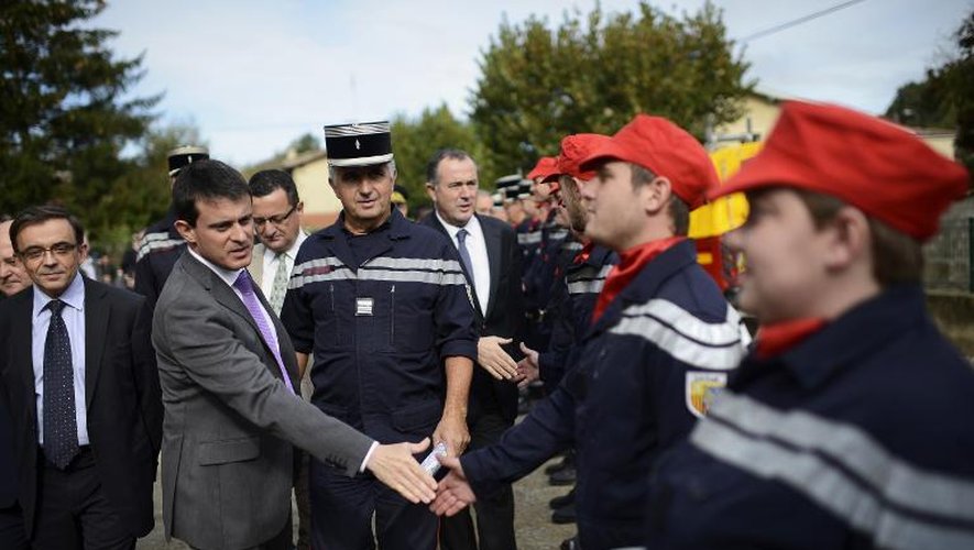 Manuel Valls (2è g) félicite les pompiers le 29 octobre 2013 à Clérieux, au sud-est de la France, pour avoir porté secours aux habitants victimes d'indondations