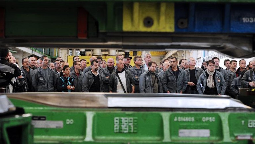 Un ouvrier d'Heuliez presse symboliquement une dernière pièce de carrosserie devant ses collègues, le 31 octobre 2013, jour de la fin des activités de l'équipementier automobile