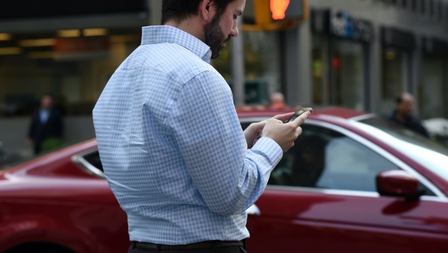 Un homme consulte son smartphone en attendant au coin de la rue, le 13 novembre 2014 à New York