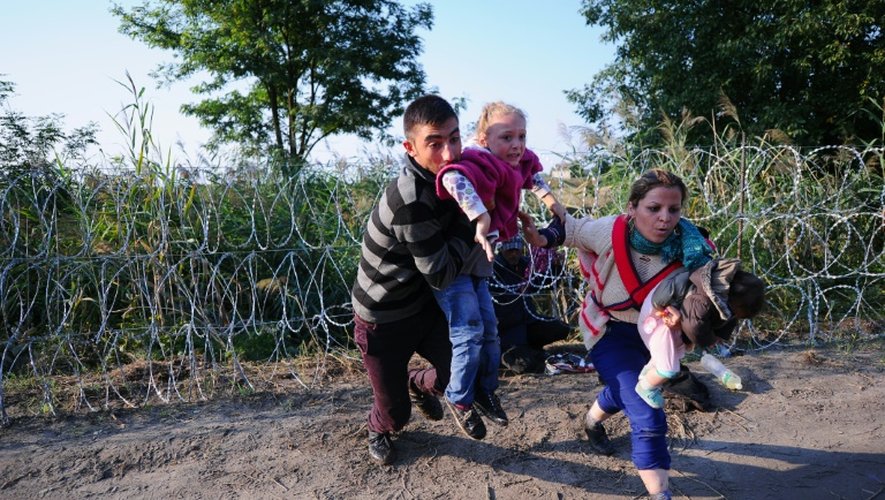 Des migrants franchissent les barbelés à la frontière entre la Hongrie et la Serbie le 27 août 2015 à Roszke