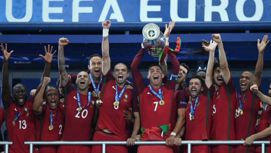 L'attaquant vedette du Portugal Cristiano Ronaldo (c) brandit le trophée entouré des ses équipiers après la victoire face à la France en finale de l'Euro au Stade de France, le 10 juillet 2016