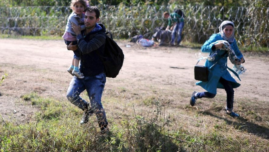 Une famille de migrants court après avoir traversé la frontière entre la Serbie et la Hongrie, près du village de Roszke, le 28 août 2015