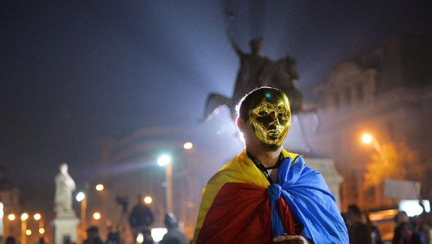 Un manifestant avec un masque en or et un drapeau roumain sur les épaules, à Bucarest, le 3 novembre 2013