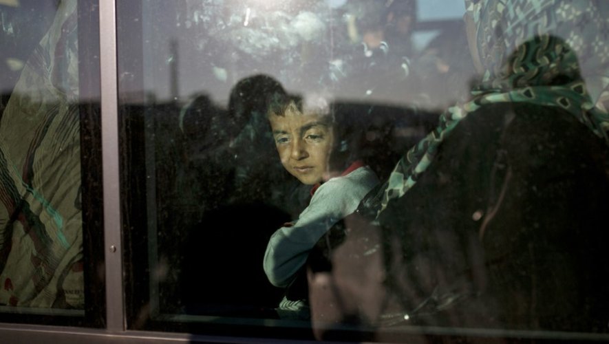 Un garçon regarde par la fenêtre d'un bus au port du Pirée, à l'arrivée d'un ferry affretté par le gouvernement pour transporter les migrants depuis les îles orientales, le 29 août 2015
