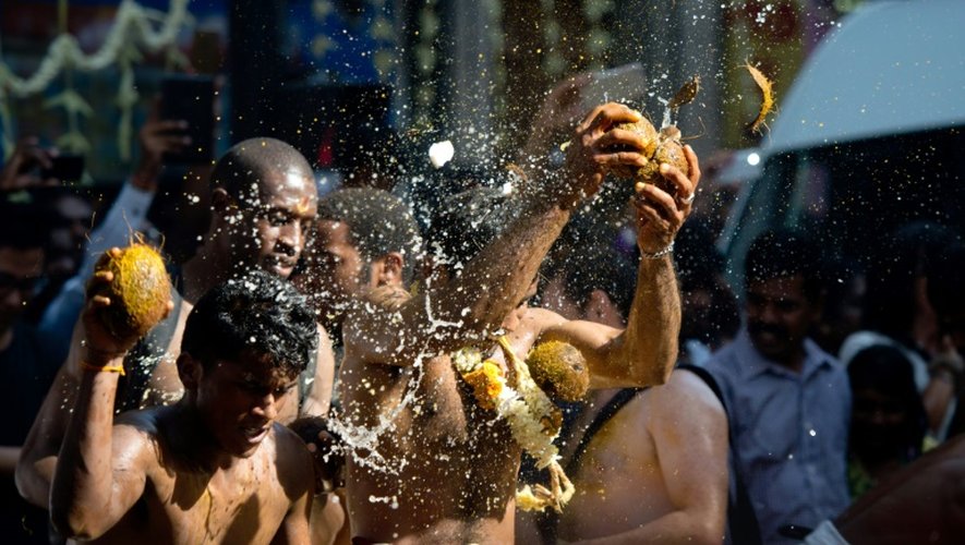 Des fidèles hindous cassent des noix de coco pour chasser le mauvais oeil et l'ego, lors de la procession en l'honneur de Ganesh, le 30 août 2015 à Paris
