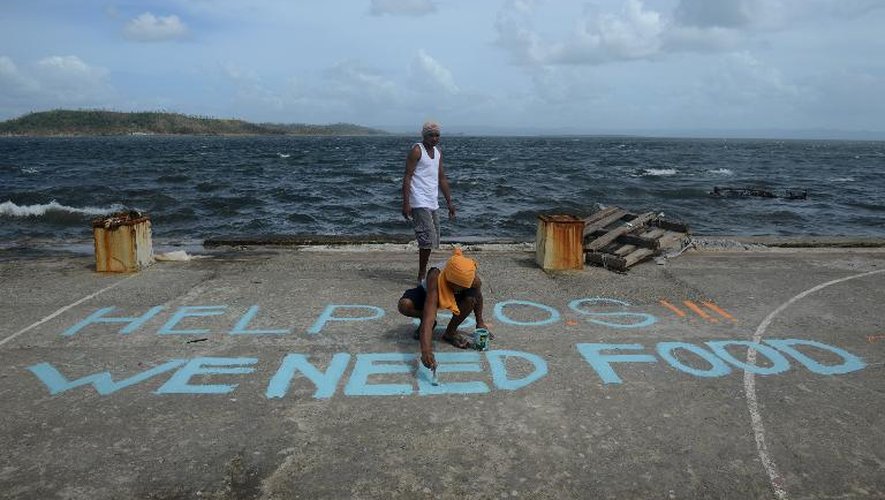 Un homme peint sur un terrain de baskeball le message "Au secours, SOS, nous avons besoin de nourriture" à Tacloban, le 11 novembre 2013