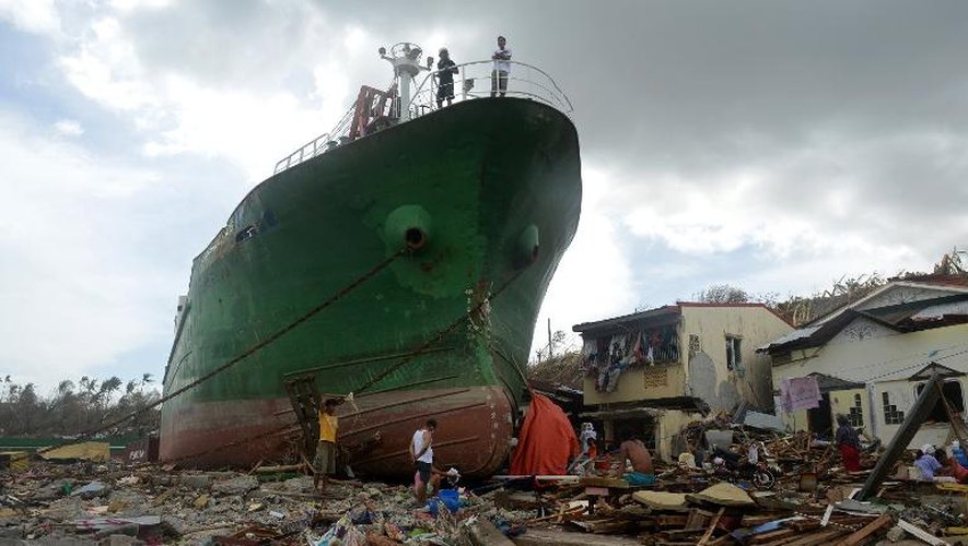 Des Philippins parmi les décombres laissés par le typhon Haiyan, près d'un bateau échoué, à Tacloban, sur l'île de Leyte, le 11 novembre 2013