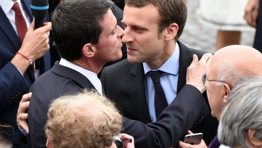 Accolade entre Manuel Valls et Emmanuel Macron à leur arrivée le 14 juillet 2016 sur les Champs Elysées à Paris pour le traditionnel défilé