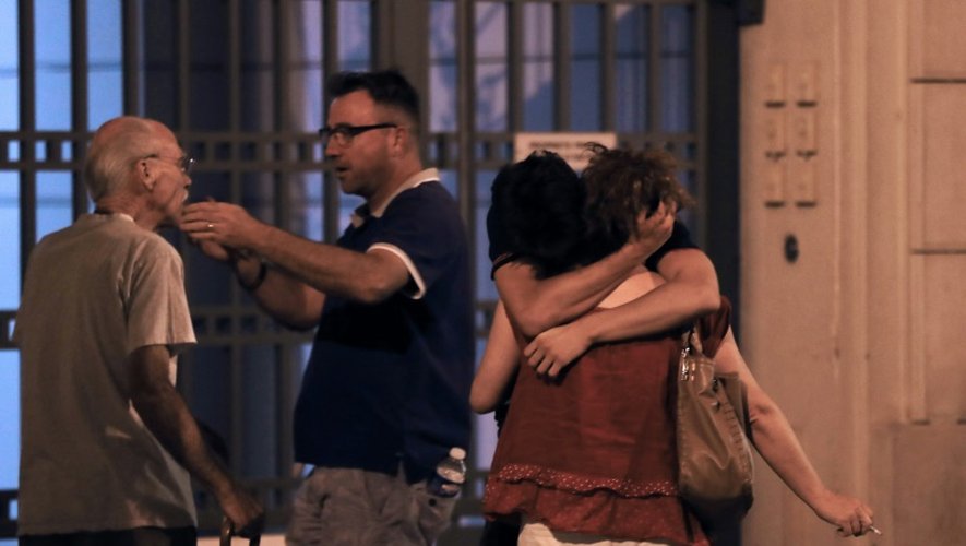 Des personnes réagissent, émues, après l'attaque de Nice en France, le 15 juillet 2016