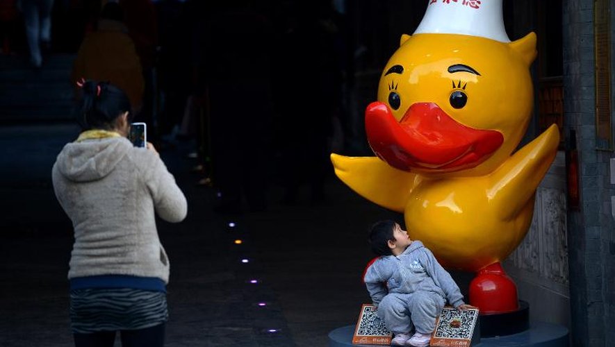 Une mère photographie son enfant devant un canard géant en plastique, le 12 novembre 2013 à Pékin