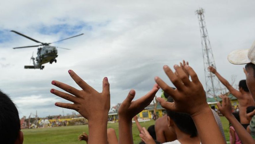 Des survivants du typhon saluent l'arrivée d'un hélicoptère américain le 16 novembre 2013 à Giporlos