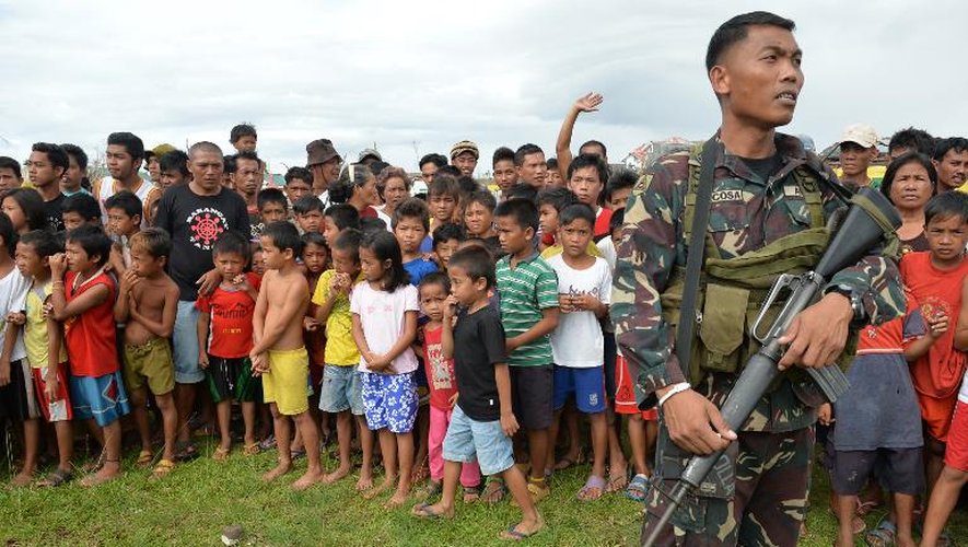 Un soldat philippin monte la garde devant une file de survivants le 16 novembre 2013 à Giporlos