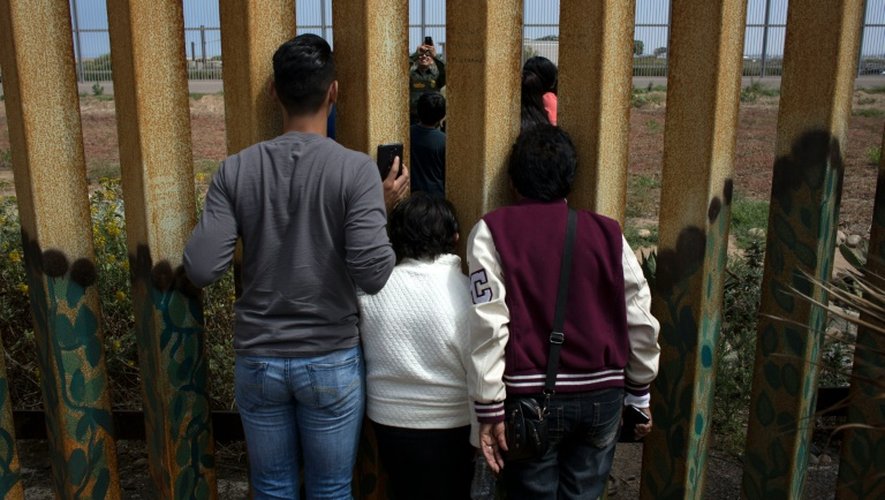La famille Rosete-Quintana se retrouve des deux côtés de la frontière entre les Etats-Unis et le Mexique, sous les yeux d'un agent américain, le 2 juillet 2016 à Tijuana