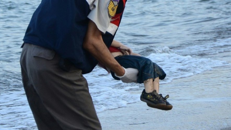 Un policier turc porte le corps d'un enfant migrant mort noyé, sur une plage de Bodrum, en Turquie, après le naufrage d'un bateau transportant des réfugiés, le 2 septembre 2015