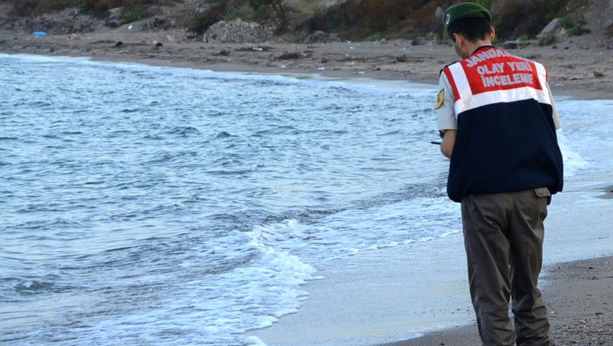 Un policier turc se tient près du corps d'un enfant migrant mort noyé, sur une plage de Bodrum, au sud de la Turquie, après le naufrage d'un bateau transportant des réfugiés, le 2 septembre 2015