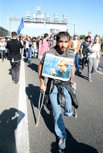 Un handicapé porte le portrait de la chancelière Angela Merkel alors qu'il fait partie du cortège des migrants qui se lance vers la frontière autrichienne, le 4 septembre 2015 à Budapest