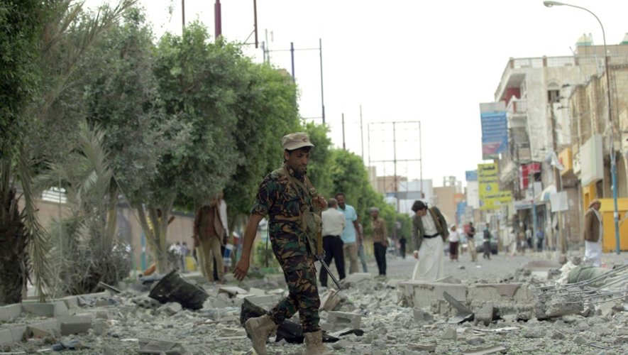 Un rebelle Houthi marche au milieu d'immeubles détruits après des frappes de la coalition arabe, le 5 septembre 2015 à Sanaa