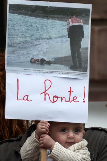 Un enfant tient une pancarte montrant la photo du petit garçon syrien découvert mort sur une plage turque, le 5 septembre 2015 lors d'une manifestation à Strasbourg