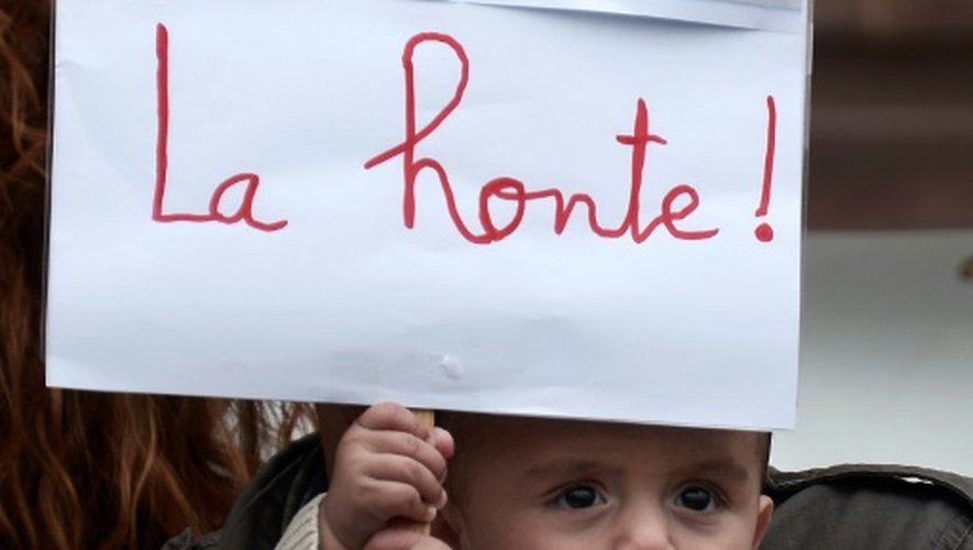 Un enfant tient une pancarte montrant la photo du petit garçon syrien découvert mort sur une plage turque, le 5 septembre 2015 lors d'une manifestation à Strasbourg