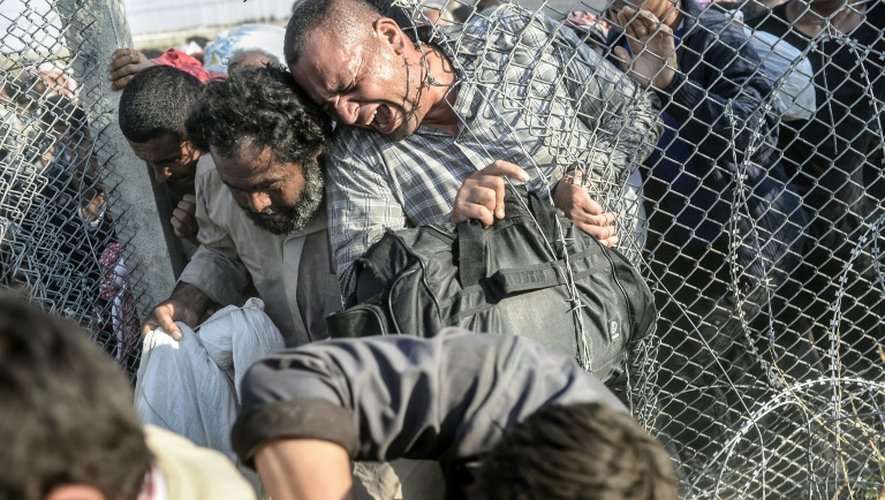Photo prise le 14 juin 2015 par le photographe de l'AFP Bülent Kiliç récompensé du Visa d'Or News à Perpignan montrant 
des Syriens fuyant la guerre passant en territoire turc au point de passage d'Akcakale dans la province de Sanliurfa