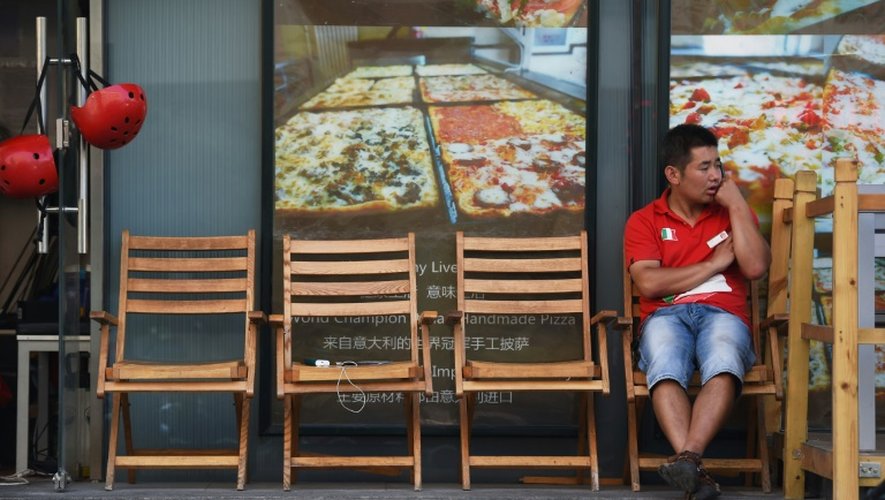 Un livreur de pizza attend une nouvelle commande devant un restaurant, le 7 septembre 2015 à Pékin