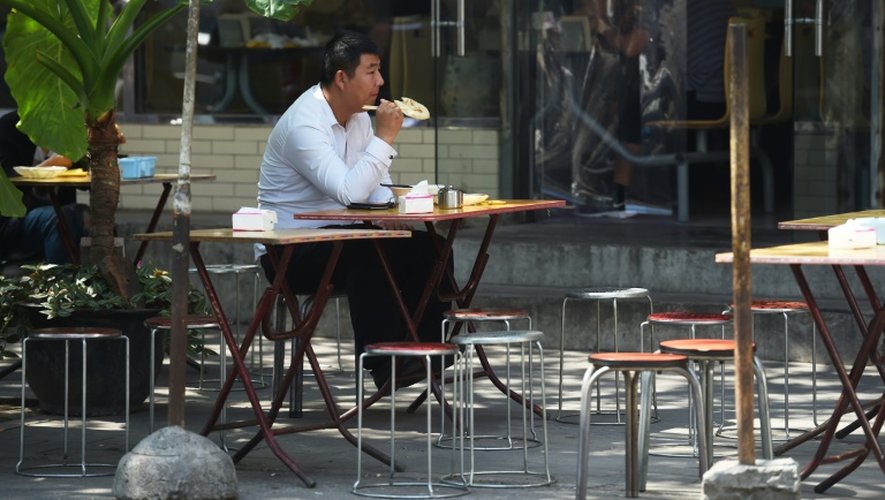 Un homme prend un repas en extérieur, devant un restaurant de Pékin, le 7 septembre 2015