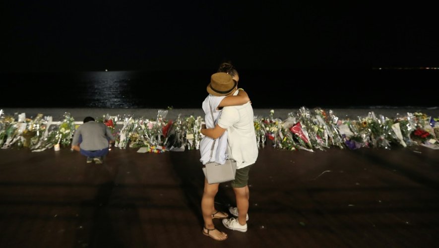 Deux personnes s'étreignent devant le mémorial improvisé pour les victimes de l'attentat de Nice, le 18 juillet 2016